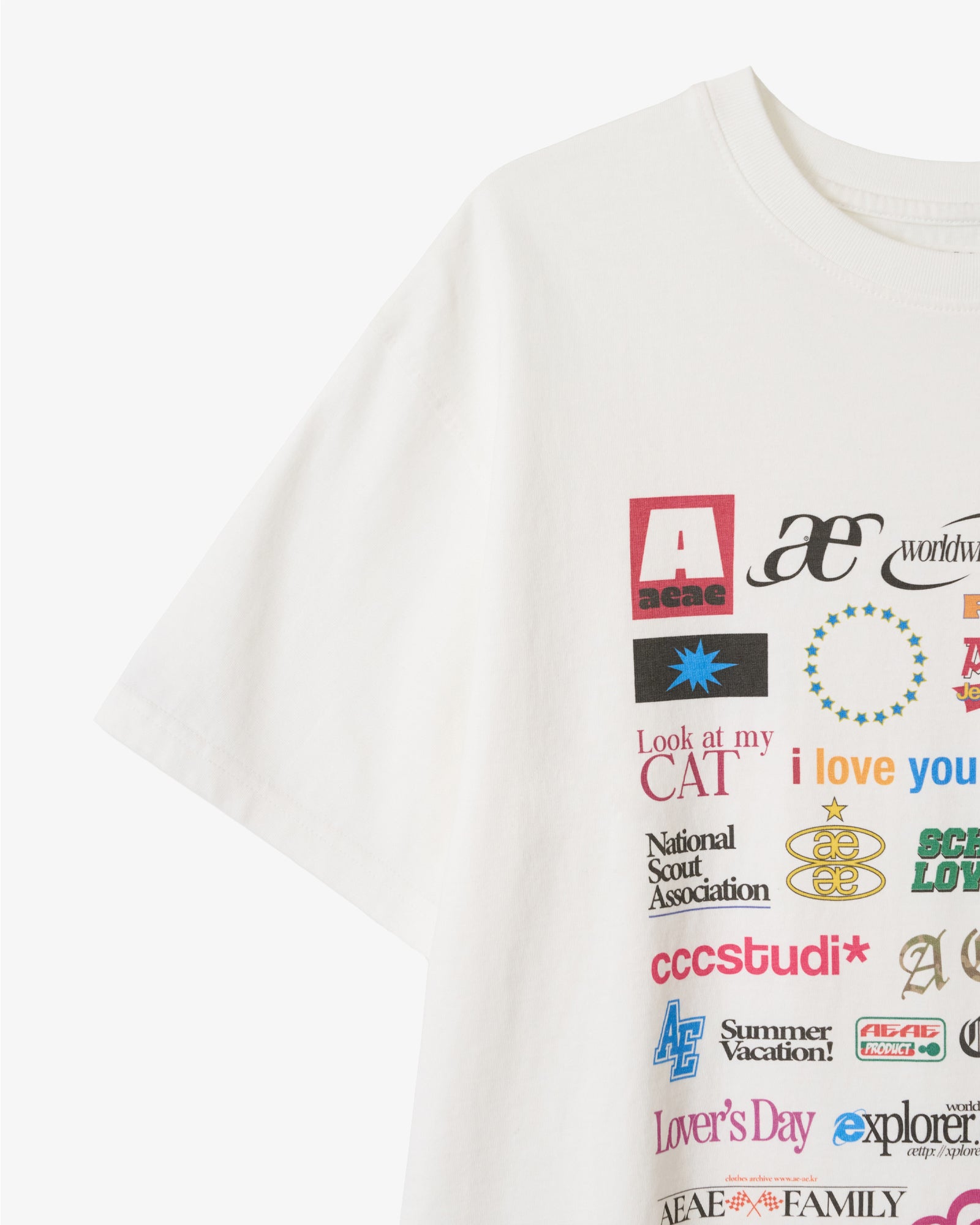 A close up on a white t-shirt from Korean brand aeae with a colorful sticker style print on the front, for sale at Shim House