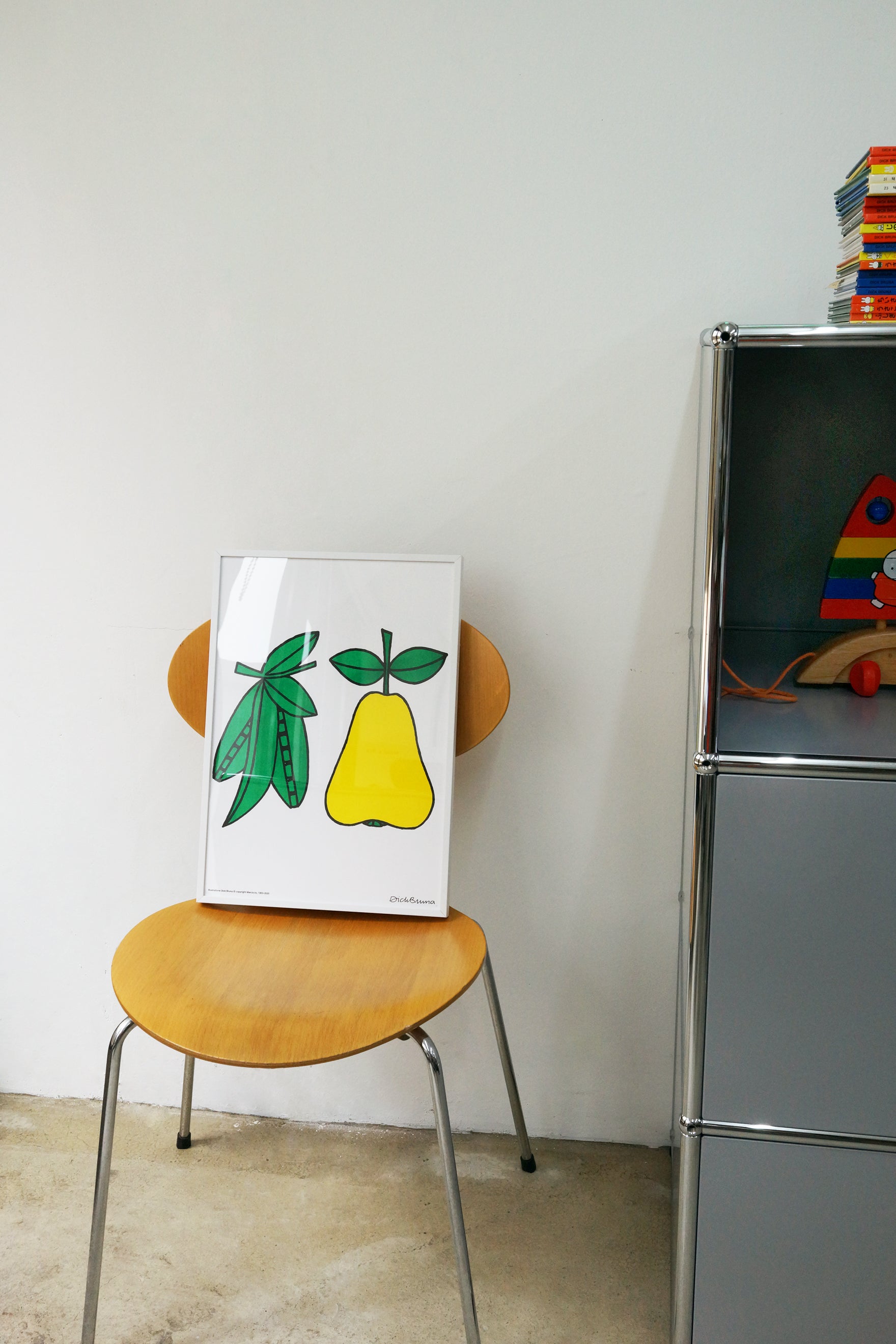 An A3 sized poster sitting on a chair of green peas in their pods and a yellow pear, painted by Dick Bruna, printed by Korean brand Zero Per Zero and for sale at Shim House