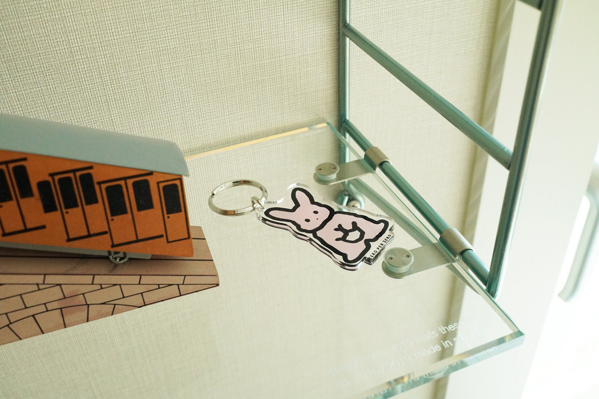 A pink rabbit drawing keyring placed on a glass table, created by a Korean brand called Zero Per Zero and for sale at Shim House